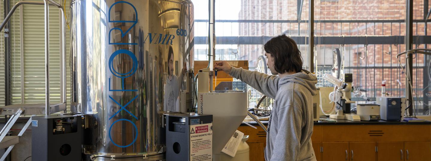 A person in a lab loads a sample into a Bruker Avance III-HD 600 NMR Spectrometer.