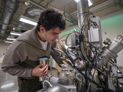 A person leans over a large spherical machine with many cables and components sticking out of it.