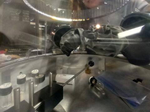 A scientist uses the Noble Dome's built-in gloves to manipulate an object inside the closed dome.