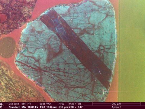 A microscope image of shocked quartz, which shows a diagonal black line across the surface of a quartz crystal.
