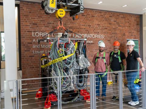 Staff pose with the S/TEM column as it is prepared to be craned down into the CAMCOR space.
